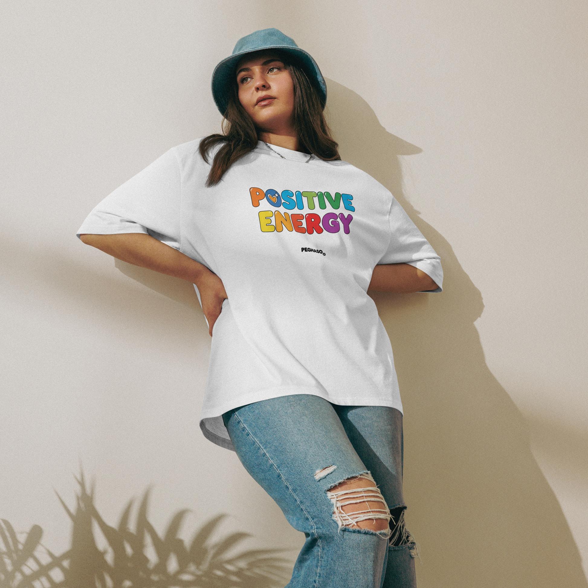 mujer vistiendo camiseta PEGHASO® POSITIVE ENERGY blanca oversize, estilo streetwear.