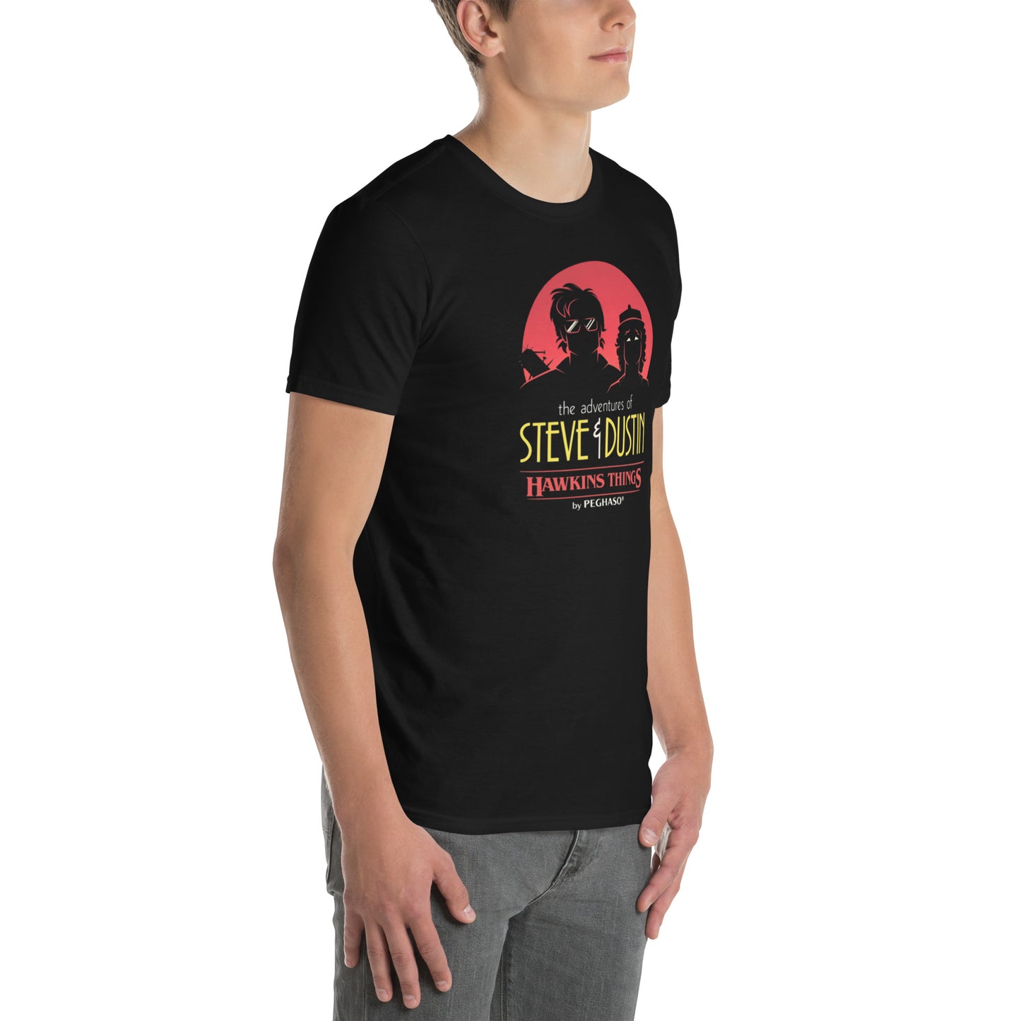 Modelo luciendo camiseta negra con diseño de Steve Harrington y Dustin Henderson estilo Batman y Robin de los 80, colección Hawkins Things de PEGHASO. Camiseta Stranger things